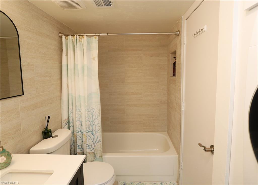 2235 San Marco Road, Unit 5204 Marco Island, FL 34145 - Photo 29 of 42 Bathroom with tile walls, shower / bath combination with curtain, and vanity