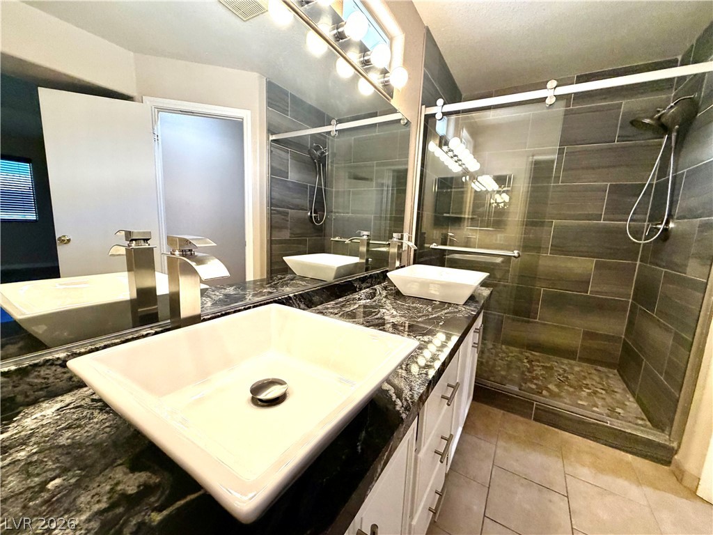 3936 Gold Point Street Las Vegas, NV 89129 - Photo 13 of 23 Dual vessel sinks adorn a spacious vanity with a sleek, walk-in shower.
