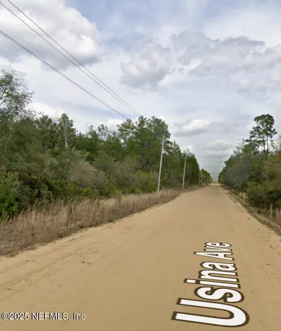 a view of a dry yard with wooden fence
