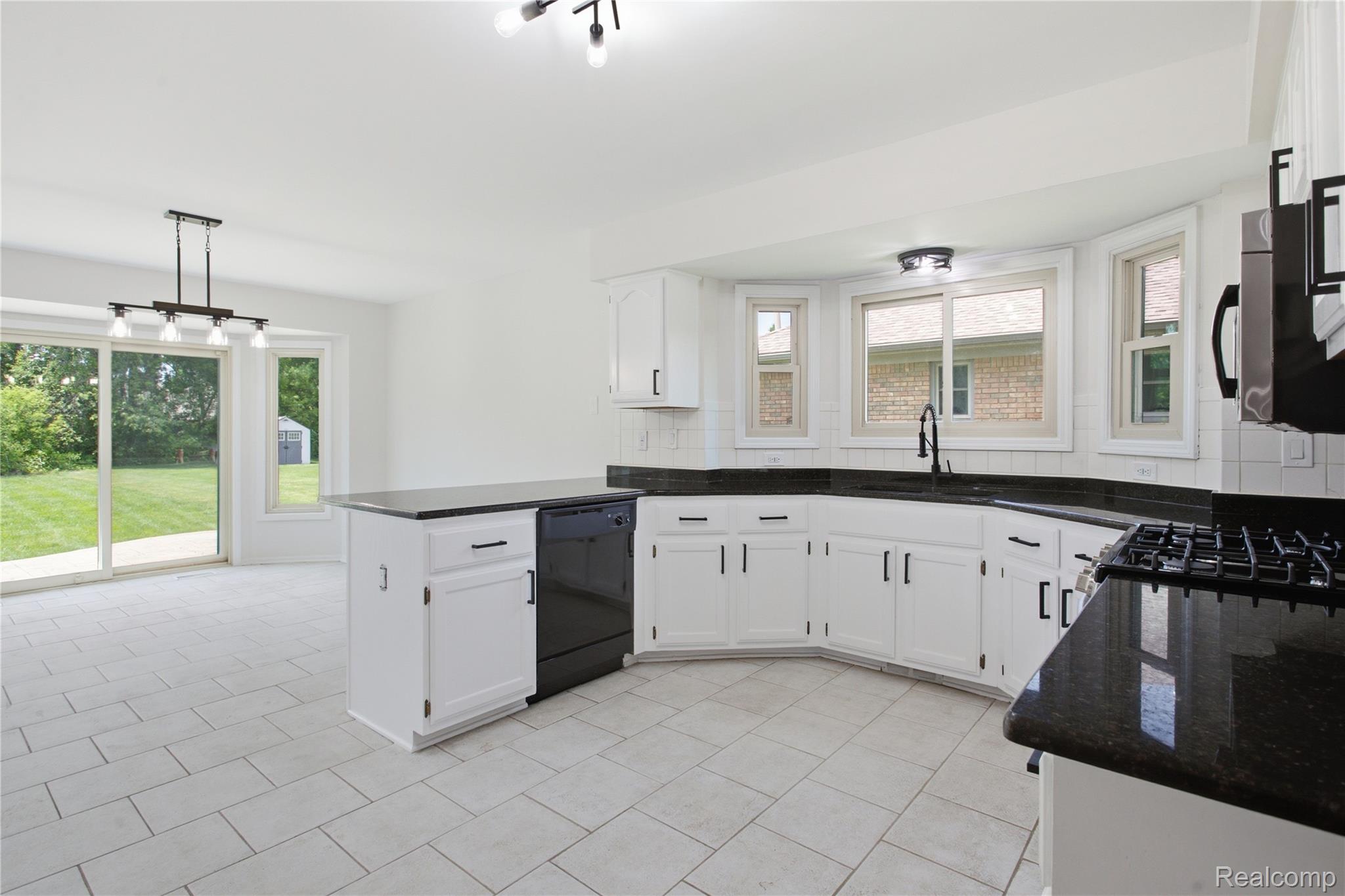 52658 Stag Ridge Drive Macomb, MI 48042 - Photo 9 of 28 Kitchen featuring white cabinetry, black countertops, and a black gas range