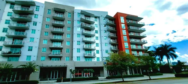 a front view of multi story residential apartment building with yard and retail shops