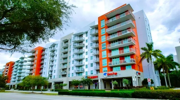 a front view of multi story residential apartment building with yard and flowers