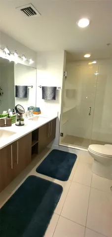 a bathroom with a sink a toilet a mirror and shower