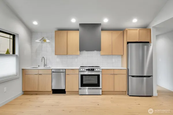 a kitchen with stainless steel appliances granite countertop a refrigerator a stove a sink and a microwave