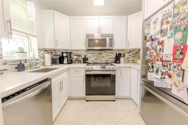 a kitchen with stainless steel appliances a sink cabinets and a window