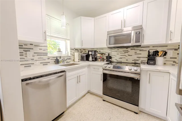 a kitchen with stainless steel appliances granite countertop white cabinets a stove top oven a sink and dishwasher