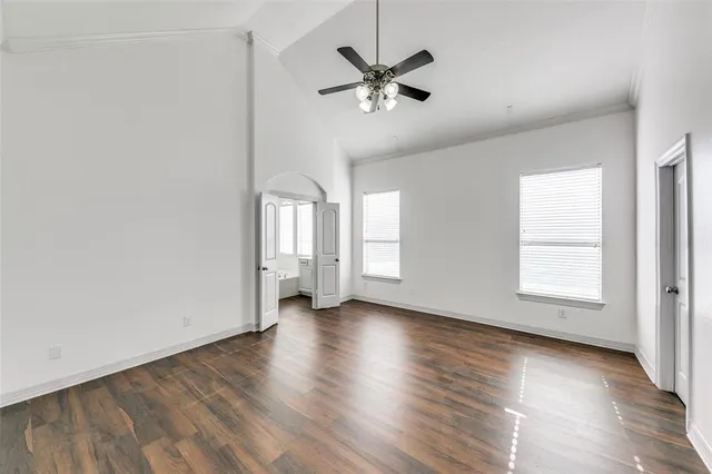an empty room with wooden floor fan and windows
