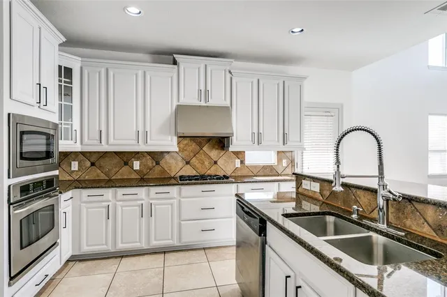 a kitchen with granite countertop a sink and white cabinets