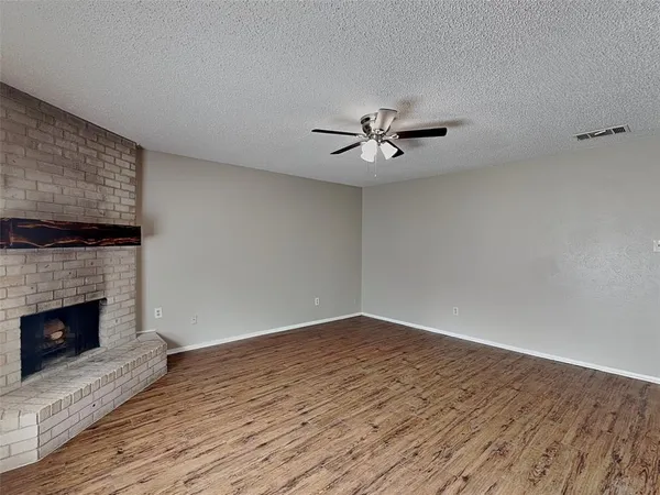 a view of an empty room with wooden floor and a fireplace