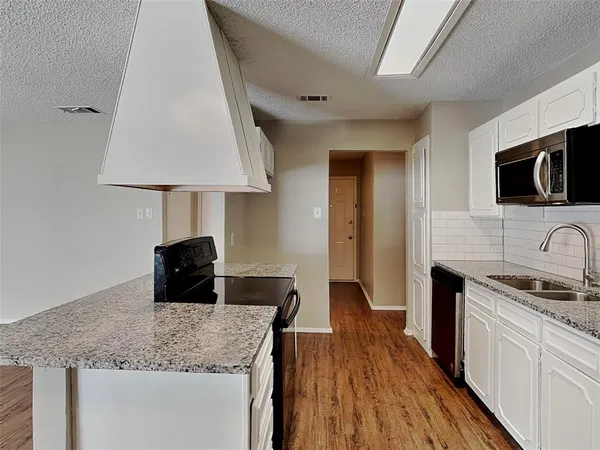 a kitchen with granite countertop a sink a stove and a wooden floor