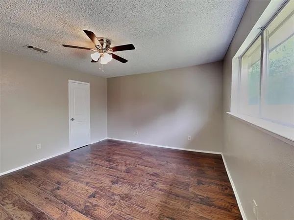 a view of empty room with wooden floor and fan