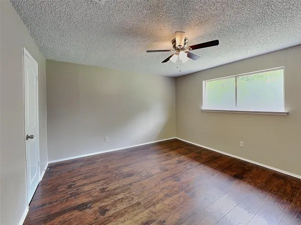 an empty room with wooden floor ceiling fan and windows