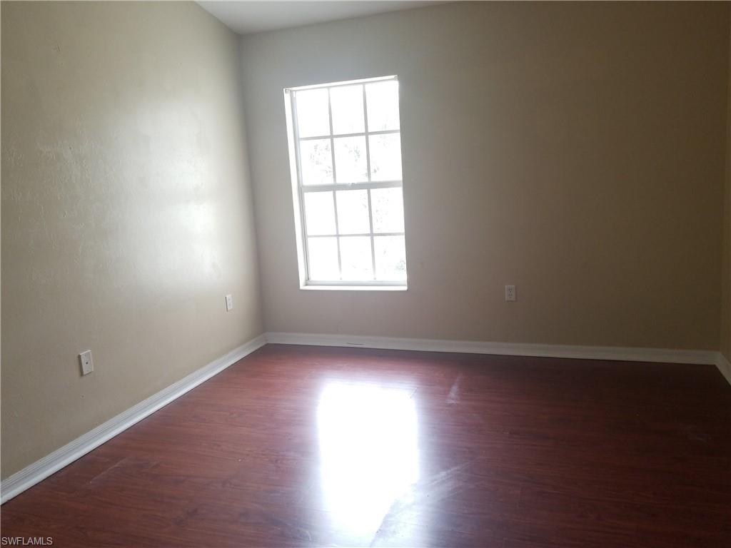 988 Hampton Circle, Unit 73 Naples, FL 34105 - Photo 11 of 22 an empty room with wooden floor and windows