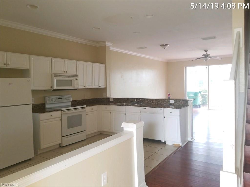 988 Hampton Circle, Unit 73 Naples, FL 34105 - Photo 5 of 22 a kitchen with granite countertop white cabinets and white appliances