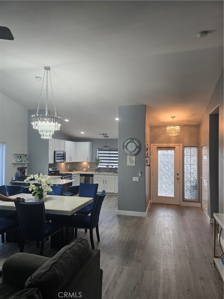 33860 Bell Thousand Palms, CA 92276 - Photo 9 of 49 a view of a dining room and livingroom with furniture wooden floor a rug a painting and a chandelier