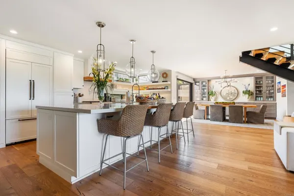 a kitchen with stainless steel appliances kitchen island granite countertop a table chairs in it and a wooden floors