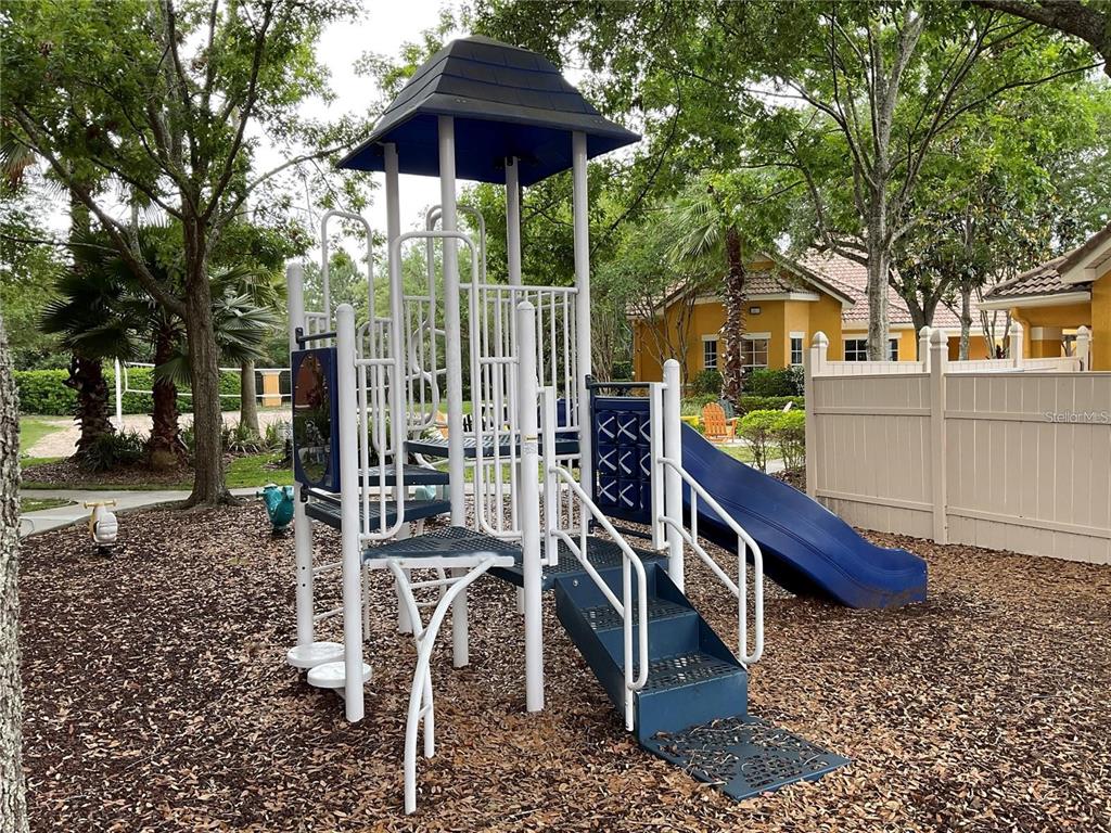8813 Villa View Circle, Unit 104 Orlando, FL 32821 - Photo 13 of 14 a view of a wooden deck with chairs and table under an umbrella