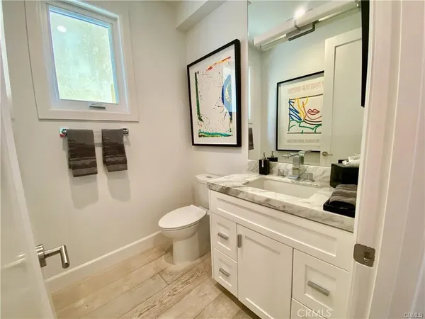 a bathroom with a granite countertop sink toilet and painting