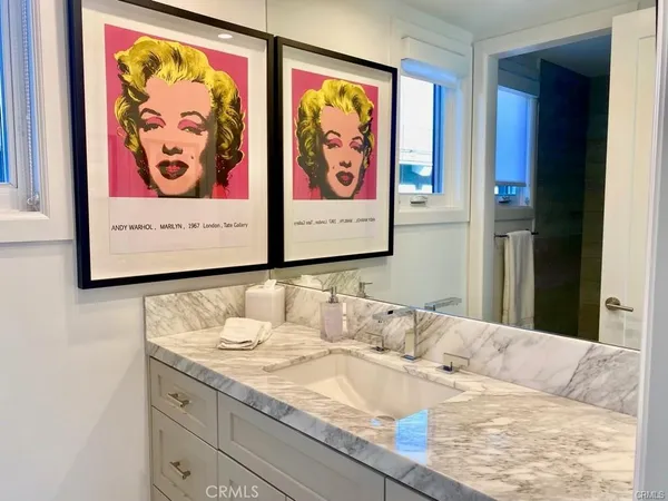 a bathroom with a granite countertop sink and a painting on the wall