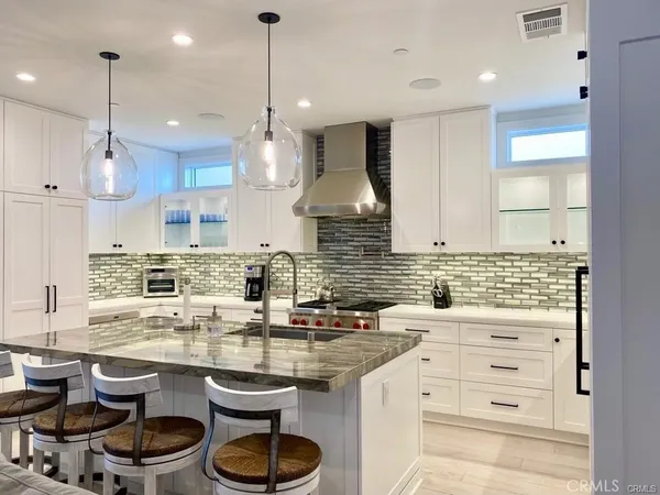 a kitchen with stainless steel appliances a dining table chairs sink and cabinets