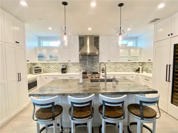 a kitchen with granite countertop a dining table chairs and white cabinets
