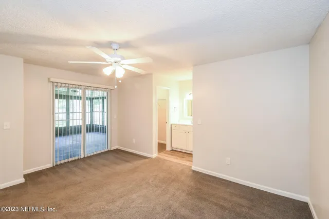 an empty room with a ceiling fan and a window