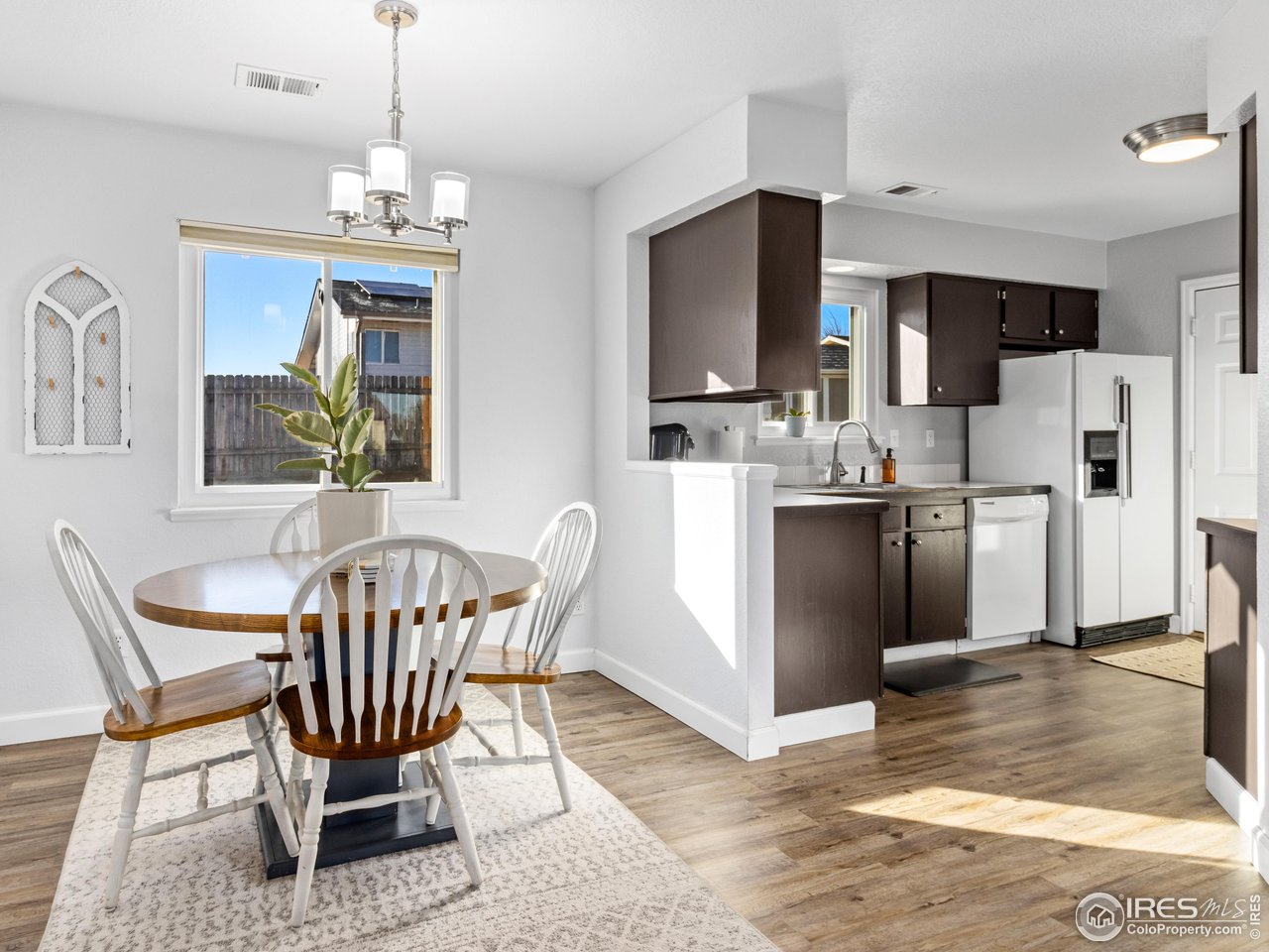 4610 Homestead Court Greeley, CO 80634 - Photo 6 of 18 a dining room with stainless steel appliances kitchen island granite countertop a refrigerator a stove a microwave oven a dining table and chairs with wooden floor