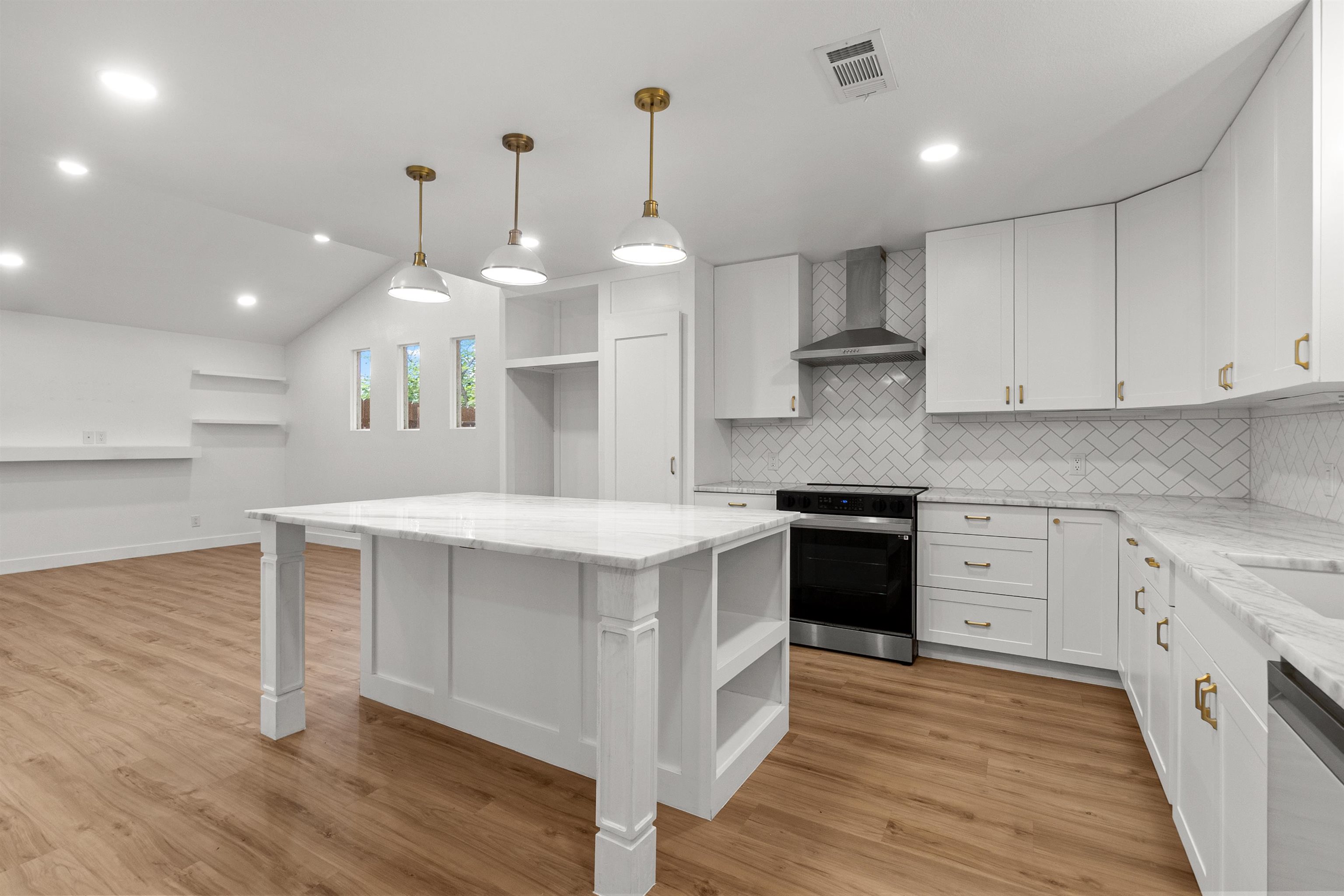 409 Ave R Marble Falls, TX 78654 - Photo 8 of 20 a kitchen with kitchen island a stove a sink a refrigerator white cabinets and wooden floor