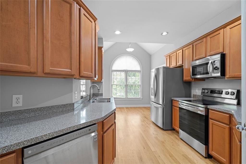 2313 Manor Avenue Atlanta, GA 30344 - Photo 7 of 31 a kitchen with stainless steel appliances granite countertop a stove a sink dishwasher a refrigerator and a microwave oven with wooden floor