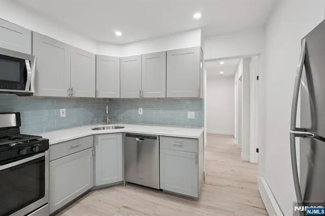 a kitchen with white cabinets sink and stainless steel appliances