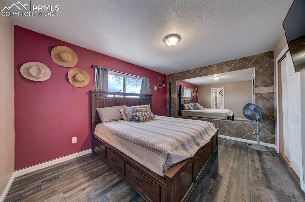 1421 Querida Drive Colorado Springs, CO 80909 - Photo 35 of 49 a bedroom with a bed and a bookshelf with wooden floor