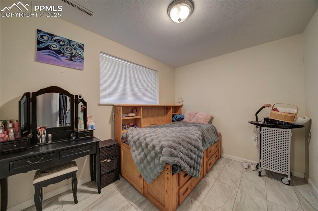 1421 Querida Drive Colorado Springs, CO 80909 - Photo 44 of 49 a bedroom with a bed and a potted plant