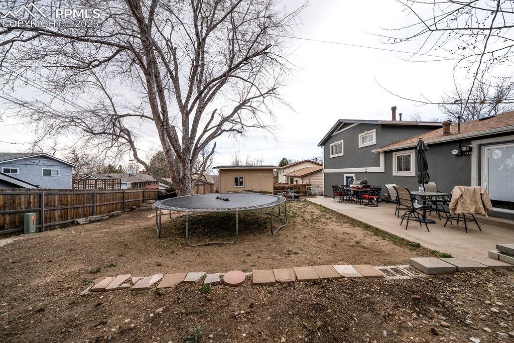 1421 Querida Drive Colorado Springs, CO 80909 - Photo 7 of 49 a view of a yard with a house and a tree