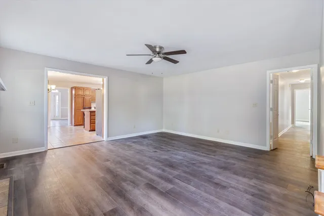 a view of an empty room with window and hardwood floor