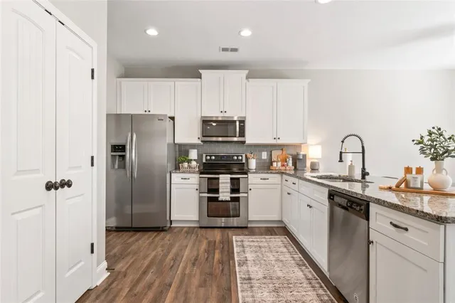 a kitchen with granite countertop a counter space chairs stainless steel appliances and cabinets
