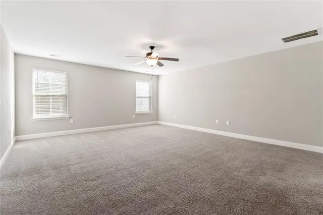 an empty room with chandelier fan and windows