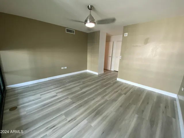 a view of empty room with wooden floor and fan