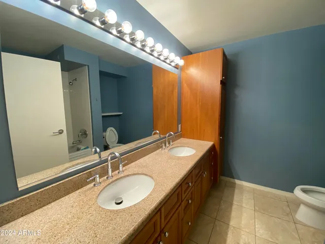 a bathroom with a granite countertop double vanity sink and a mirror