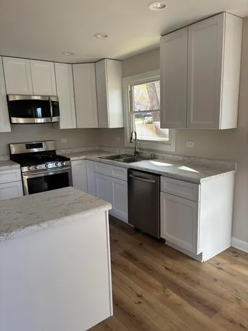 a kitchen with stainless steel appliances granite countertop a stove a sink and a microwave