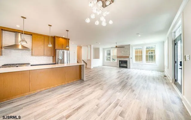 a large kitchen with kitchen island a stove a sink dishwasher and a fireplace with wooden floor