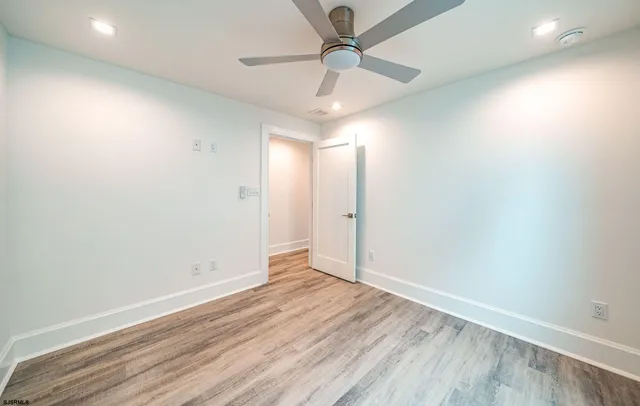 an empty room with wooden floor fan and windows