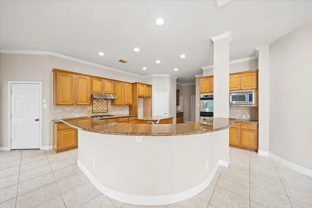 a view of a kitchen with kitchen island a sink a counter top space and stainless steel appliances