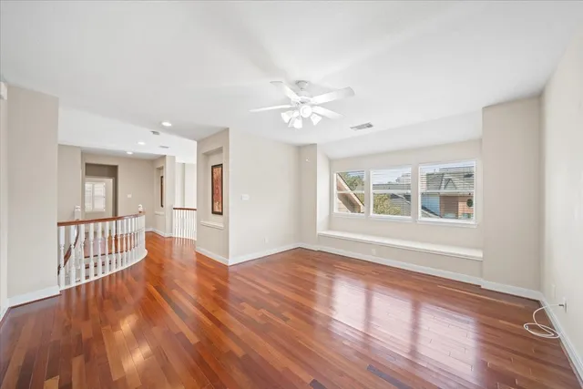 a view of an empty room with window and wooden floor