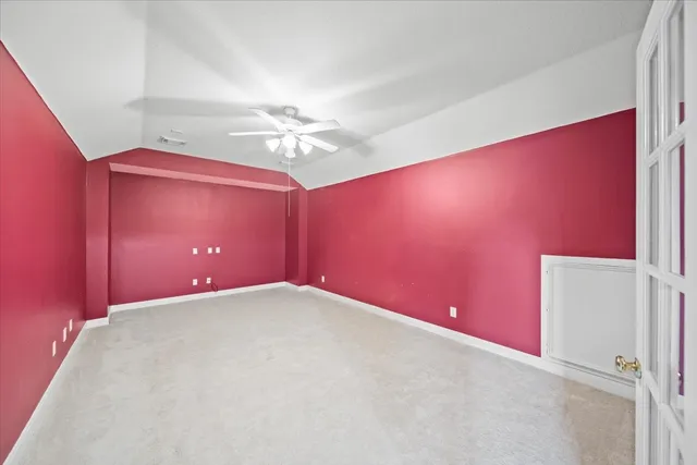 an empty room with a chandelier fan and a window