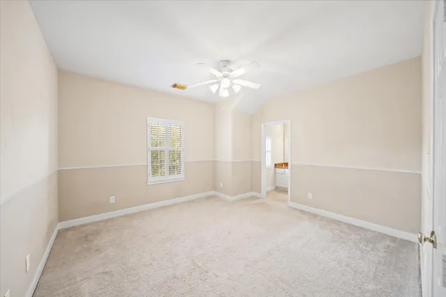 an empty room with chandelier fan and windows