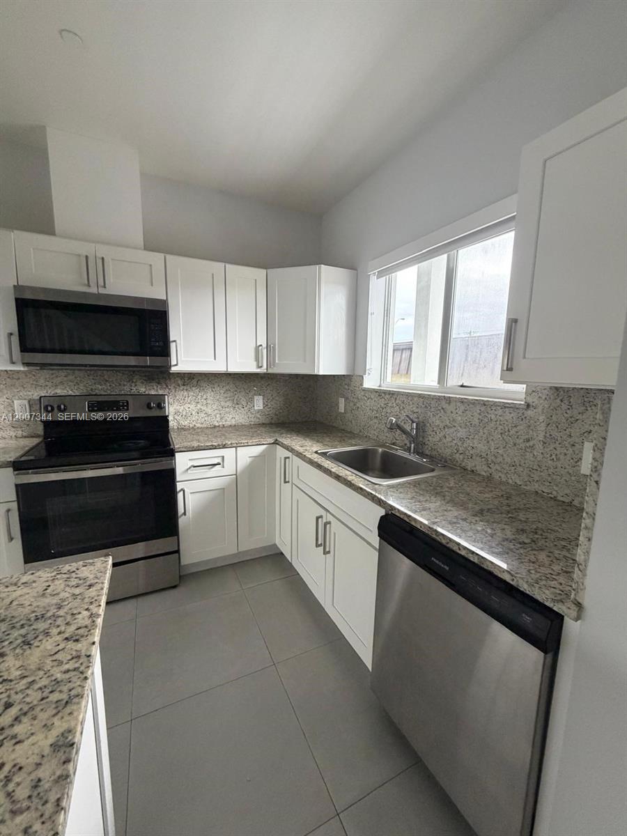 381 East 50th Street, Unit 6 Hialeah, FL 33013 - Photo 7 of 37 a kitchen with granite countertop white cabinets appliances a window and a sink