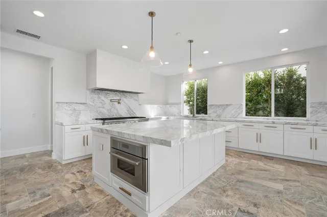 a kitchen with kitchen island granite countertop a stove and a sink