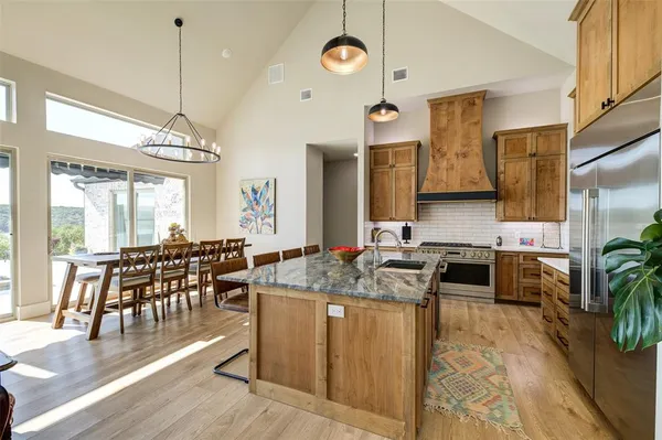 a kitchen with stainless steel appliances granite countertop a stove a sink dishwasher and a flat screen tv with kitchen view