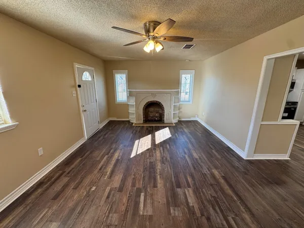 a view of an empty room with wooden floor and a fireplace