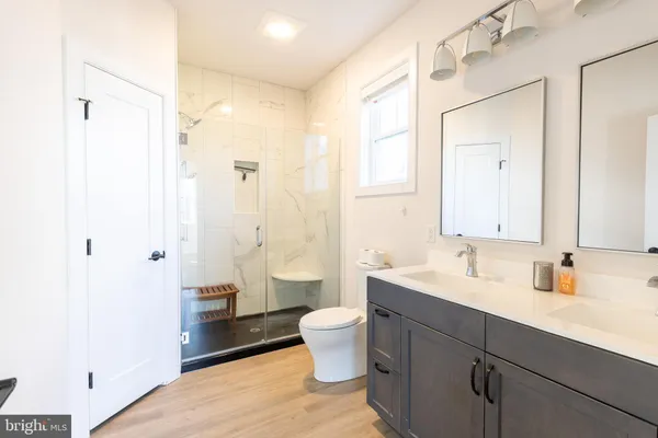 a bathroom with a double vanity sink toilet mirror and bathtub